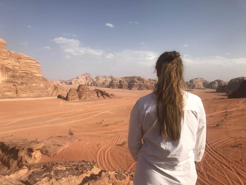 Vrouw kijkt naar woestijn met zand en rotsen