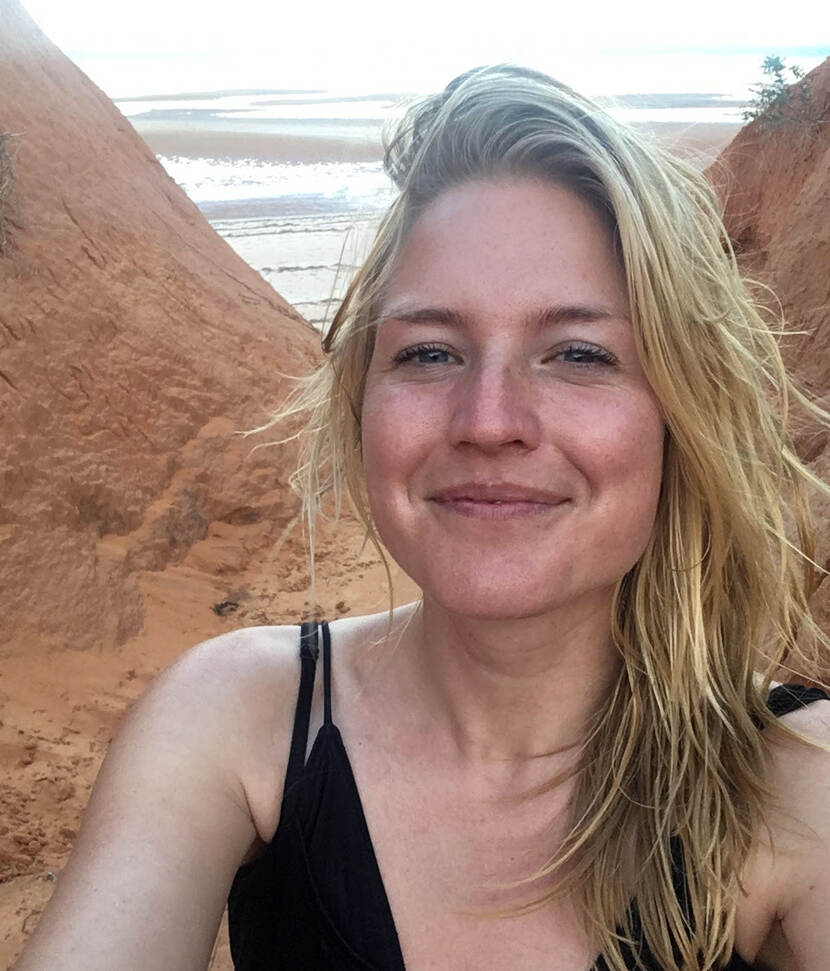 Portret van jonge vrouw met zandhopen en zee op achtergrond
