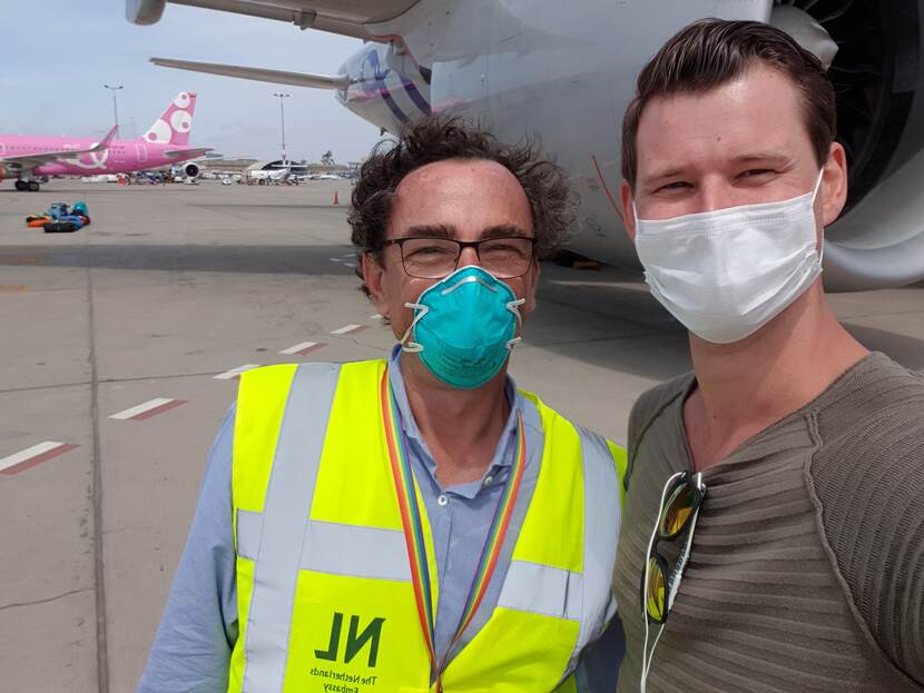 Twee mannen met mondmasker bij vliegtuig