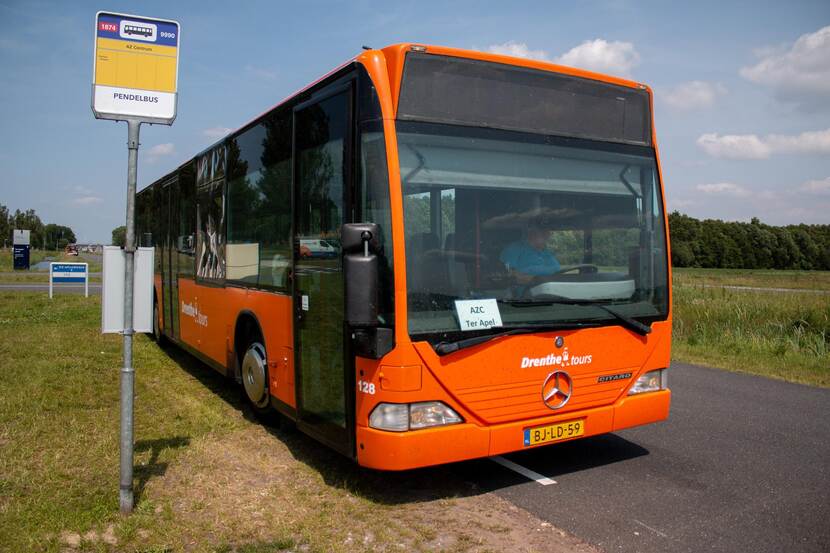 De oranje pendelbus staat stil bij een bushalte.
