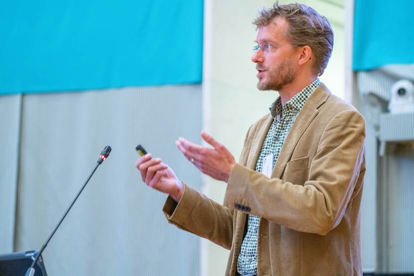 Spreker Marten Schoonman staat bij de microfoon en vertelt over het ontstaan van de Theory of Change