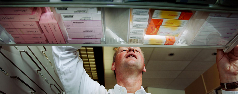 Witte mannelijke apotheker opent een lade met medicijnen