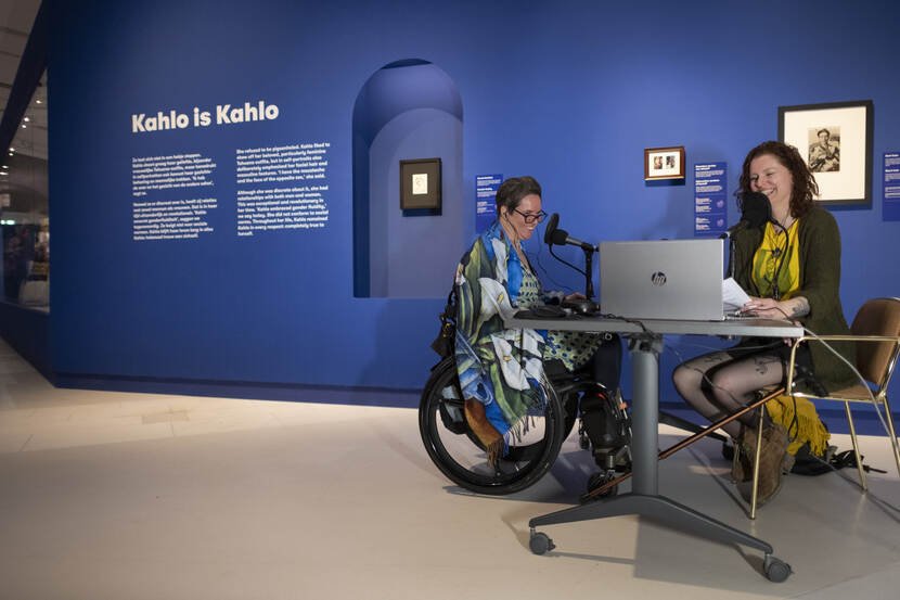 Vrouw achter bureau en vrouw in rolstoel in het Drents Museum bij expositie over Frieda Kahlo
