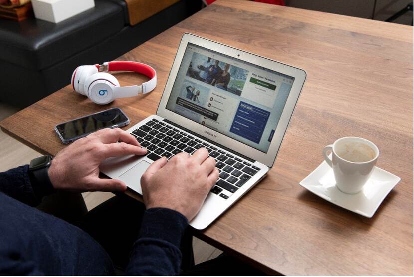 Laptop op een tafel met twee handen en een koptelefoon