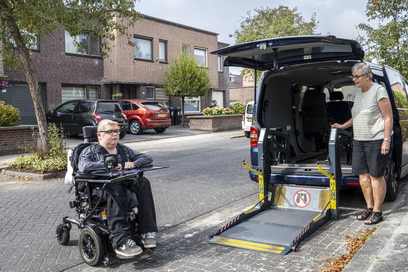 Vrouw in rolstoel en een speciale rolstoelvriendelijke vervoersauto