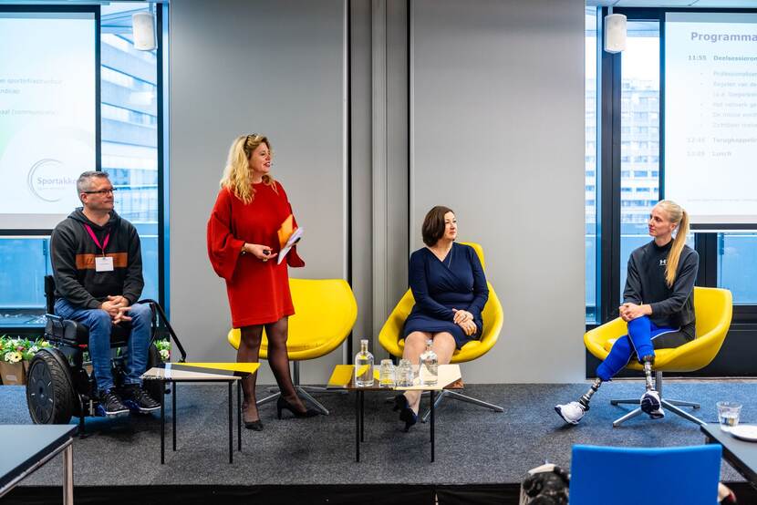 Presentatie met vier mensen, waarvan er een in een rolstoel zit
