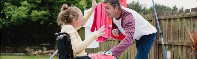 Een man en een kind in een rolstoel in een achtertuin