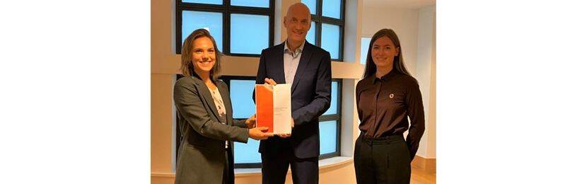 Medewerkers van het RIVM overhandigen het rapport over de effecten van de Nederlandse zorg op het milieu aan zorgminister Ernst Kuipers